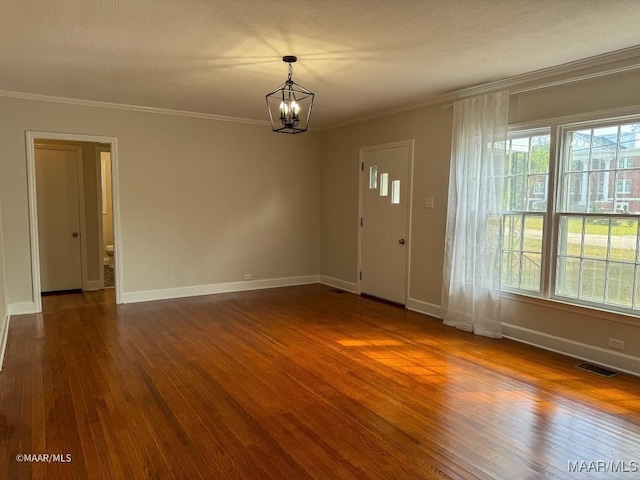 empty room featuring dark wood finished floors, crown molding, visible vents, and a wealth of natural light