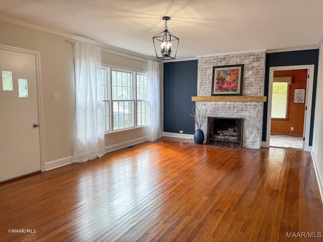 unfurnished living room featuring a chandelier, a fireplace, crown molding, and wood finished floors