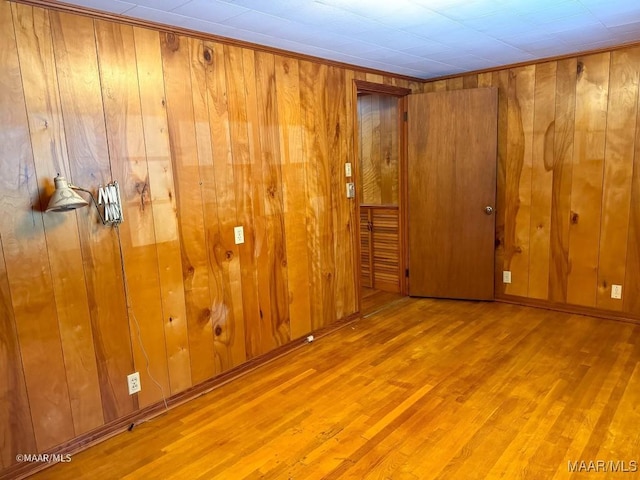 spare room with baseboards, wooden walls, and wood finished floors