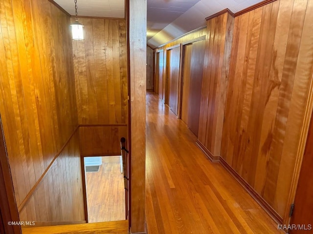 hallway featuring wood walls, lofted ceiling, and wood finished floors