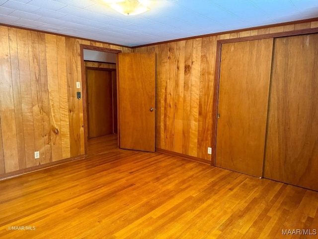 unfurnished bedroom featuring wooden walls, wood finished floors, and baseboards