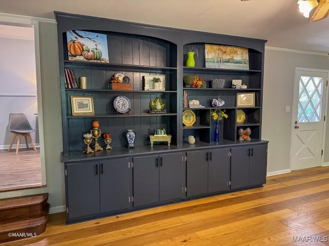 interior space with baseboards, wood finished floors, and crown molding