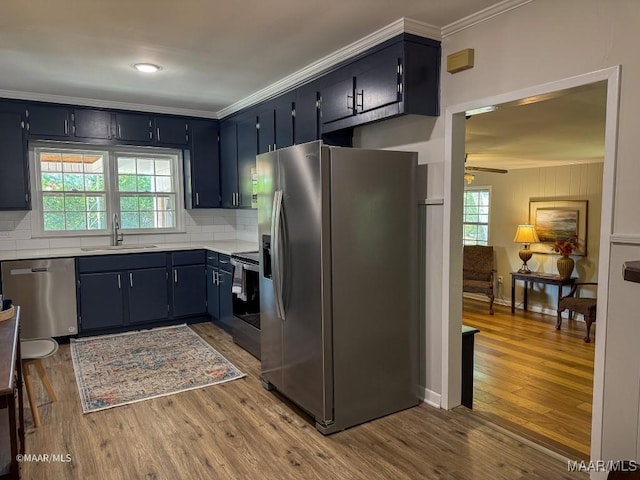 kitchen featuring a sink, ornamental molding, wood finished floors, and stainless steel appliances