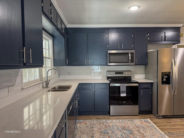 kitchen featuring light wood-type flooring, light stone counters, decorative backsplash, appliances with stainless steel finishes, and a sink