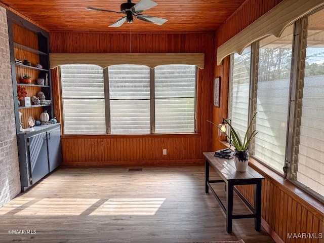 unfurnished sunroom featuring visible vents, wood ceiling, and a ceiling fan