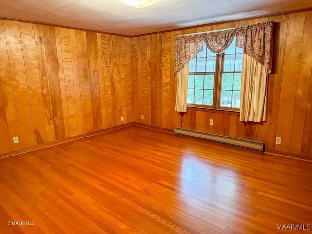 unfurnished room featuring a baseboard heating unit, baseboards, wood finished floors, and wood walls