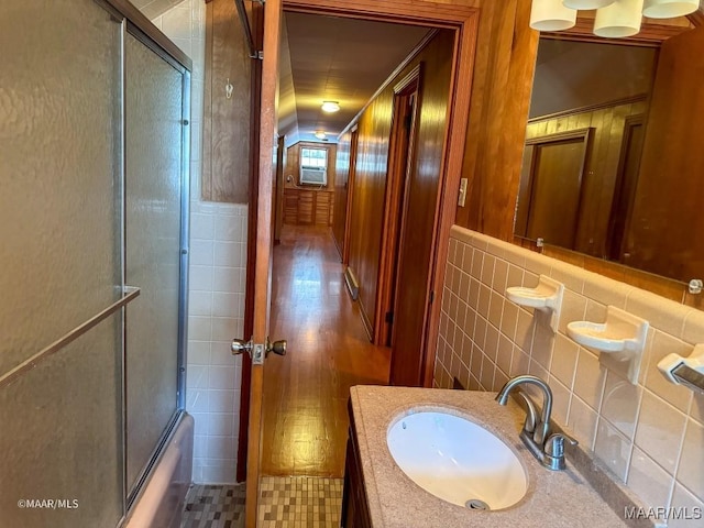 full bath with vanity, tile walls, and bath / shower combo with glass door