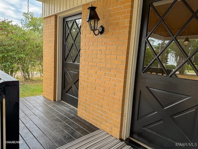 view of exterior entry featuring brick siding and board and batten siding