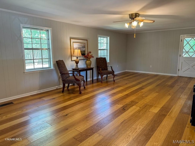 sitting room with visible vents, baseboards, ornamental molding, hardwood / wood-style floors, and a ceiling fan