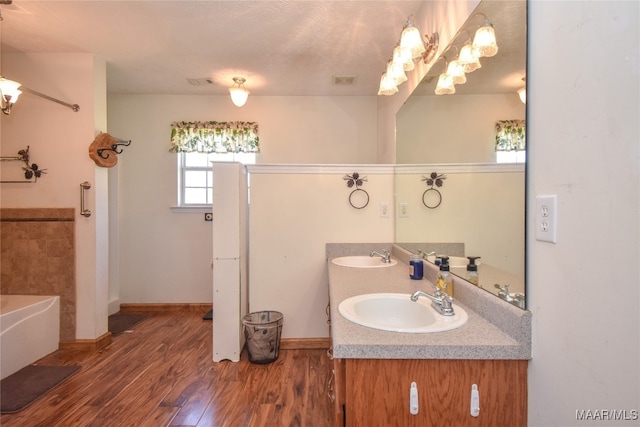 bathroom with a bath, wood-type flooring, a textured ceiling, and vanity