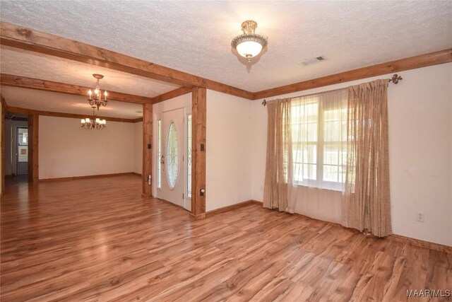 145 Cotton Ln, Deatsville, AL 36022 - spare room featuring an inviting chandelier, wood finished floors, a textured ceiling, and visible vents