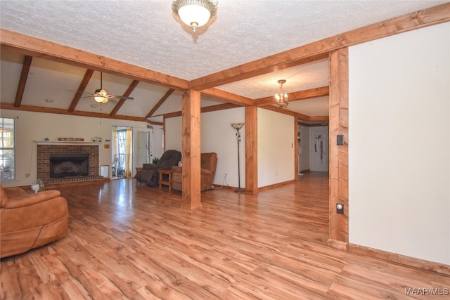 unfurnished living room featuring light wood-type flooring, ceiling fan, plenty of natural light, and a brick fireplace