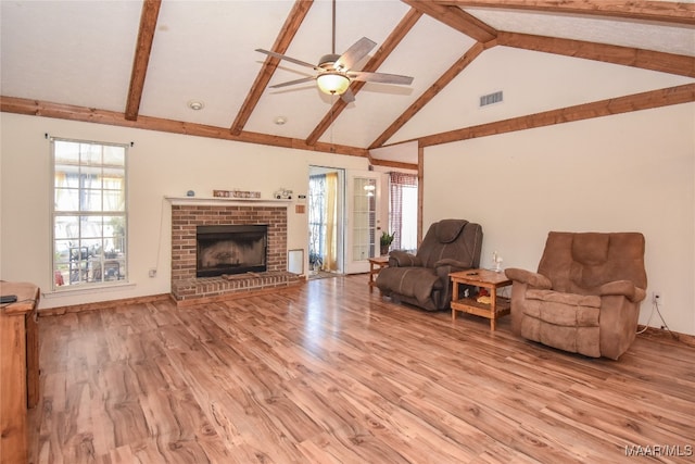 living room featuring beamed ceiling, light hardwood / wood-style floors, high vaulted ceiling, a brick fireplace, and ceiling fan