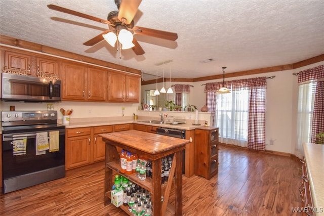 kitchen with a textured ceiling, decorative light fixtures, light hardwood / wood-style floors, stainless steel appliances, and ceiling fan