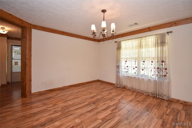 spare room featuring a textured ceiling, a notable chandelier, and wood-type flooring