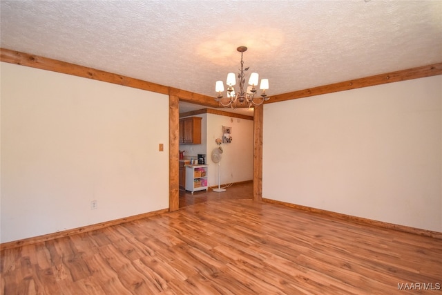 unfurnished dining area with wood-type flooring, an inviting chandelier, and a textured ceiling