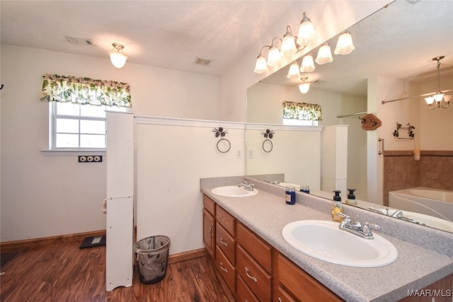 bathroom with vanity, a textured ceiling, wood-type flooring, and a washtub