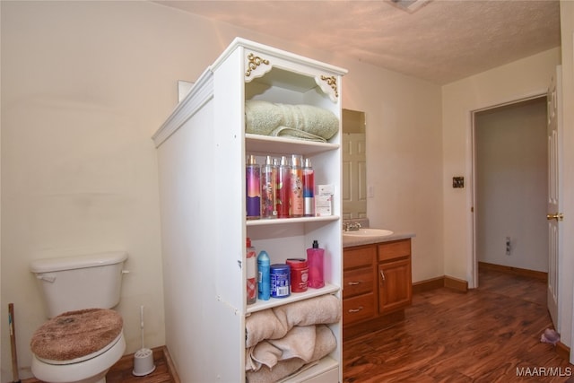 bathroom featuring a textured ceiling, vanity, toilet, and hardwood / wood-style floors