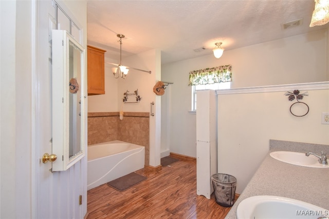 bathroom with vanity, a bath, hardwood / wood-style floors, and a textured ceiling