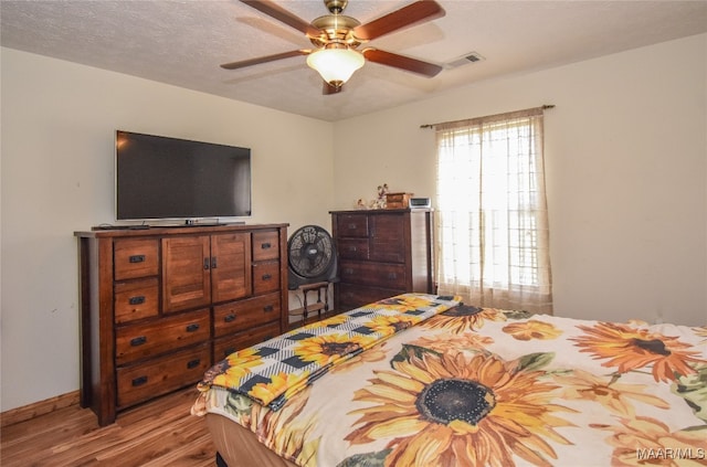 bedroom featuring multiple windows, ceiling fan, light hardwood / wood-style floors, and a textured ceiling