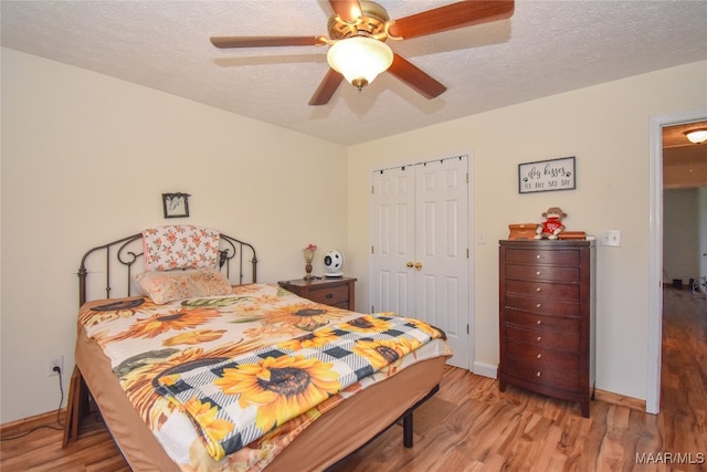 bedroom with a closet, wood-type flooring, a textured ceiling, and ceiling fan