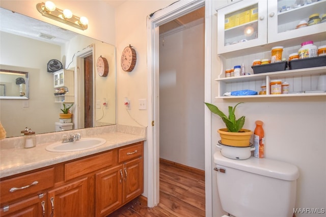 bathroom with wood-type flooring, toilet, and vanity