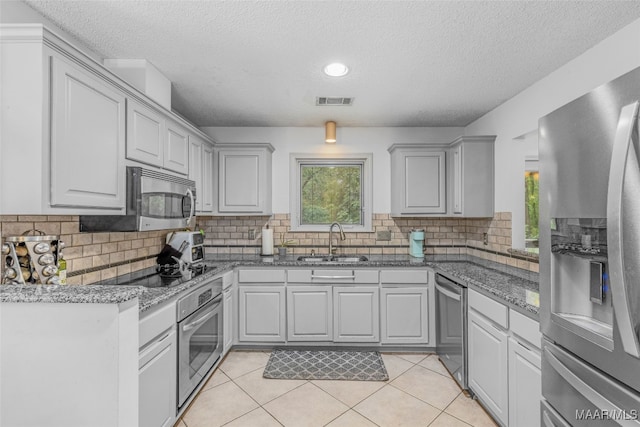 kitchen featuring stainless steel appliances, sink, tasteful backsplash, and gray cabinetry