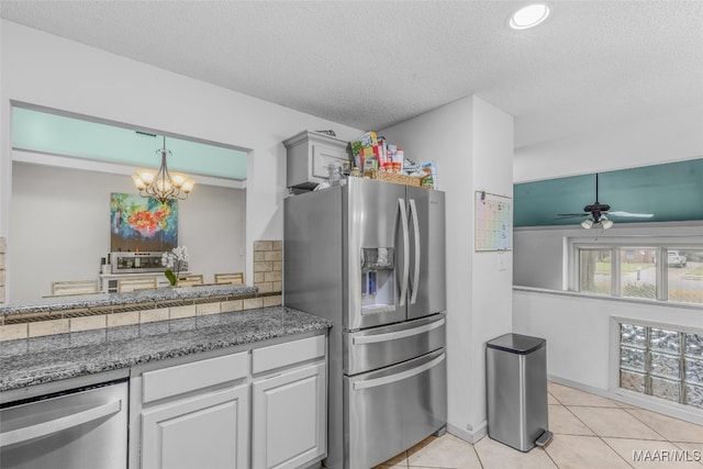 kitchen with light tile patterned floors, a textured ceiling, white cabinetry, appliances with stainless steel finishes, and ceiling fan with notable chandelier