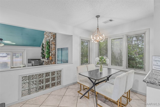 tiled dining area featuring a textured ceiling, ceiling fan with notable chandelier, and plenty of natural light