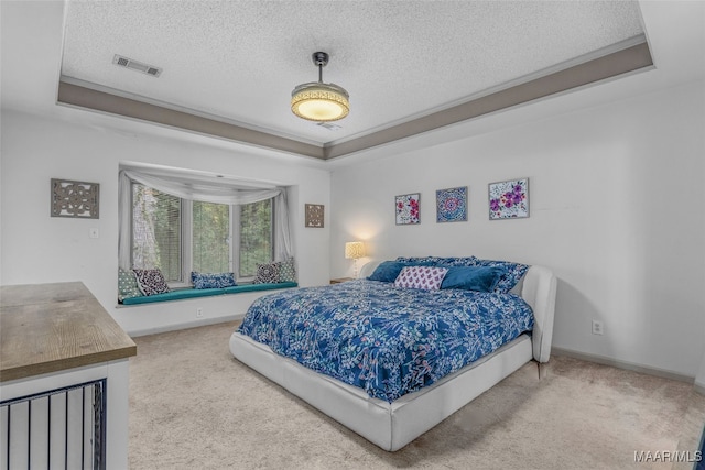 carpeted bedroom with a textured ceiling and a tray ceiling