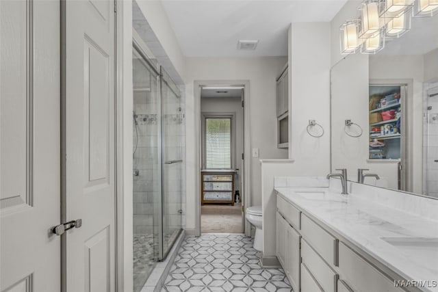 bathroom featuring tile patterned flooring, vanity, toilet, and a shower with door