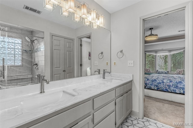 bathroom with a textured ceiling, a tile shower, vanity, and plenty of natural light