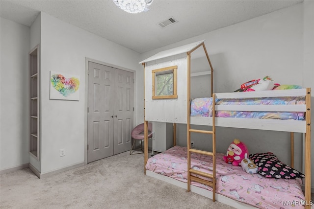 bedroom featuring a textured ceiling, light colored carpet, and a closet