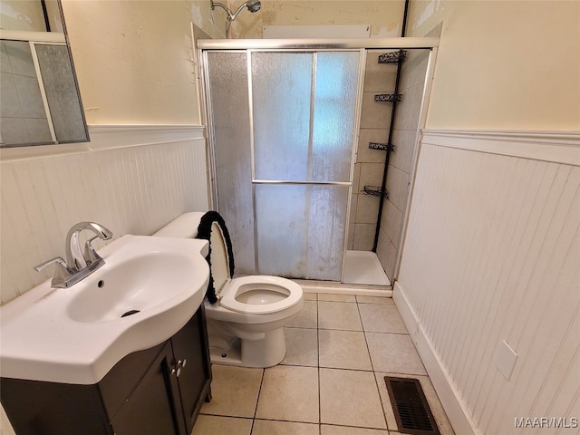 bathroom with vanity, toilet, a shower with shower door, and tile patterned flooring