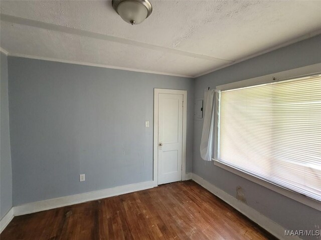 unfurnished room with wood finished floors, baseboards, ornamental molding, and a textured ceiling