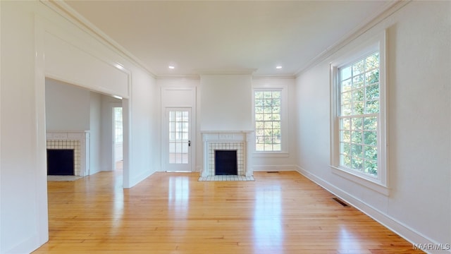 unfurnished living room with ornamental molding, light wood finished floors, and a fireplace