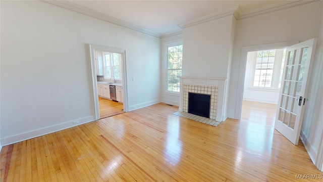 unfurnished living room featuring a fireplace, light wood finished floors, ornamental molding, and baseboards