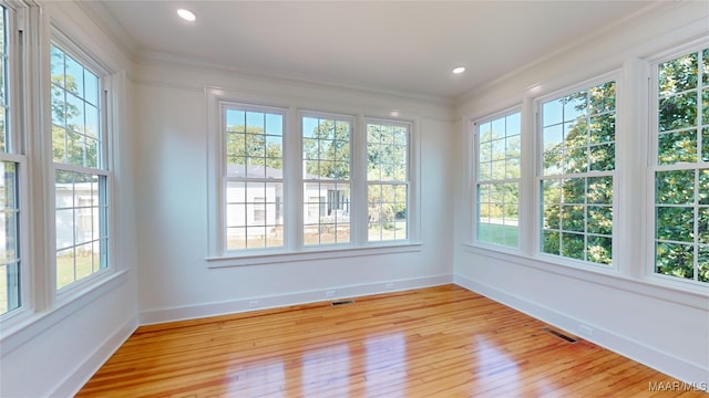 unfurnished sunroom featuring baseboards, ornamental molding, and plenty of natural light