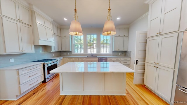 kitchen featuring a sink, light wood-style floors, tasteful backsplash, a kitchen island, and appliances with stainless steel finishes
