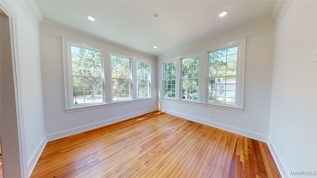 unfurnished room with visible vents, crown molding, light wood finished floors, and baseboards