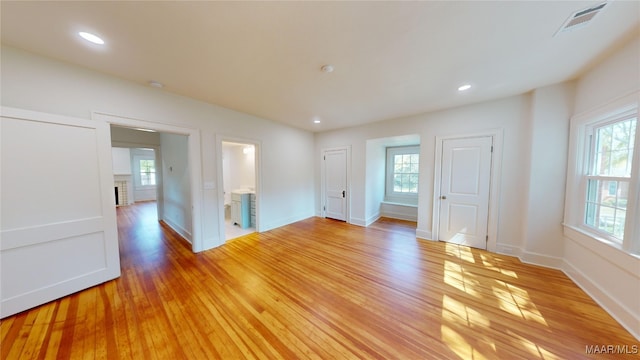 empty room featuring a wealth of natural light, visible vents, baseboards, and light wood-style floors