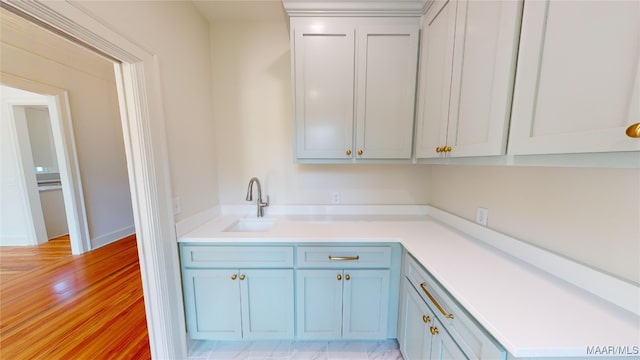 kitchen featuring light wood-type flooring, a sink, blue cabinets, and light countertops