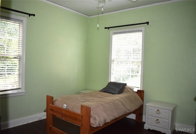 bedroom featuring crown molding, dark wood-type flooring, and ceiling fan