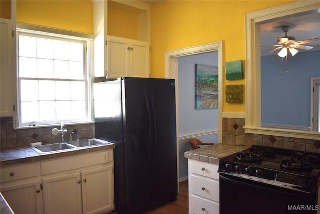 kitchen featuring sink, tile countertops, white cabinets, and black appliances