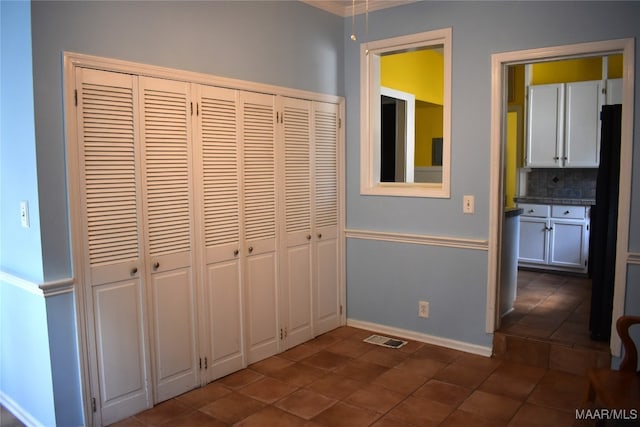 unfurnished bedroom with dark tile patterned flooring and a closet