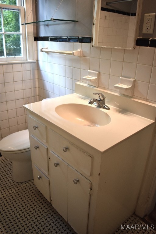 bathroom featuring vanity, toilet, tile walls, and tasteful backsplash