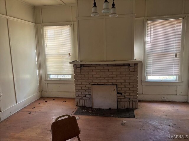 unfurnished living room featuring a chandelier, a brick fireplace, and a healthy amount of sunlight