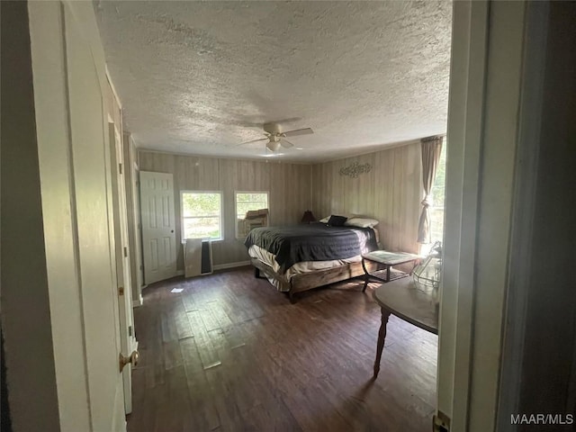 bedroom with ceiling fan, dark hardwood / wood-style flooring, and a textured ceiling