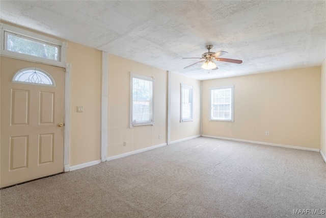 carpeted entryway featuring a textured ceiling and ceiling fan