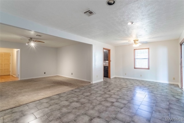 spare room featuring a textured ceiling, light colored carpet, and ceiling fan